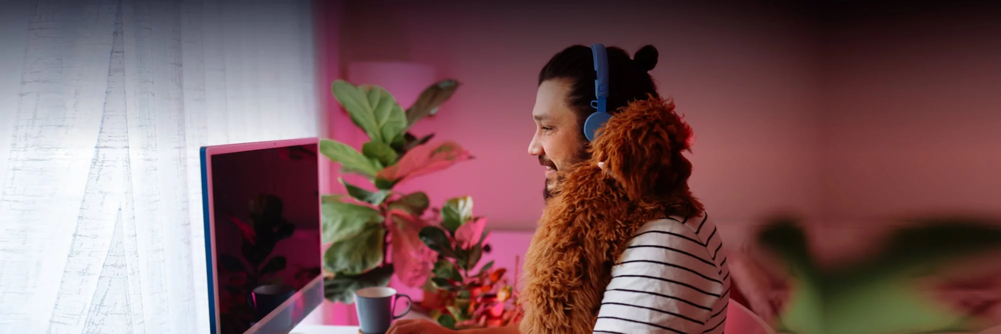 Ein Mann mit einem Hund auf der Schulter sitz vor seinem Computer.