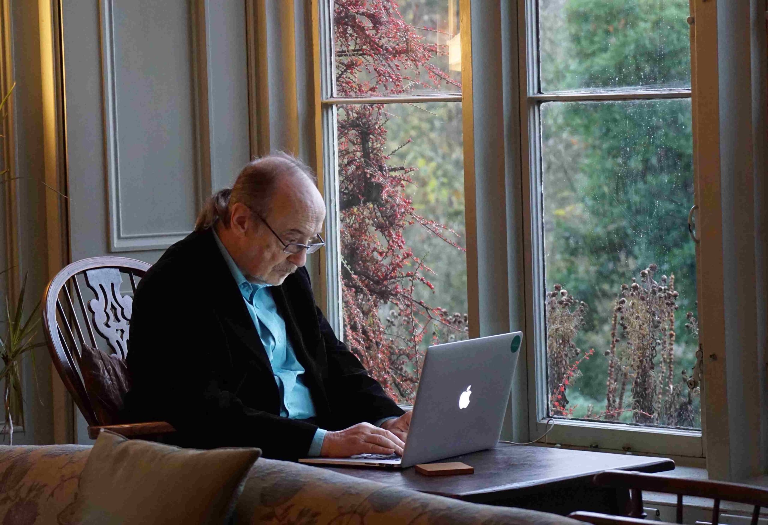 Alter Mann sitzt vor Apple-Laptop